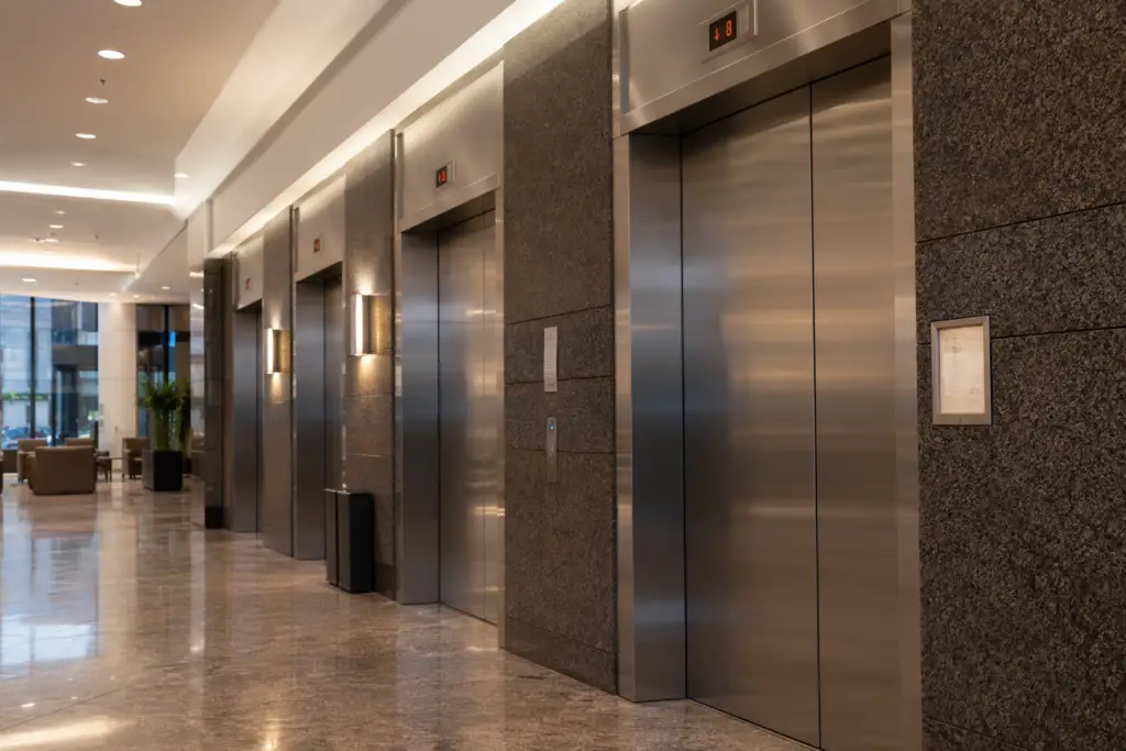 Maryland commercial elevator bank with Certificate of Operation placard visible in a Baltimore office building lobby, illustrating elevator inspection requirements MD compliance.