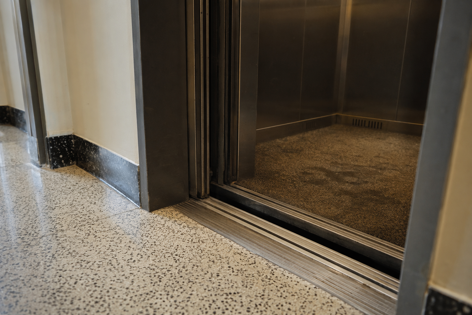 Elevator cab stopped 8 inches below floor landing in Philadelphia residential building, showing step-down tripping hazard requiring immediate emergency service