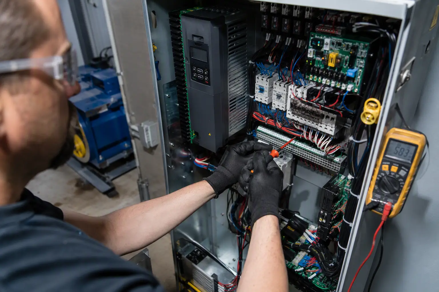 Elevator Controller Installation and Testing Elevator mechanic adjusting wiring inside a traction elevator controller cabinet in a Philadelphia commercial building machine room during final installation and testing phase.