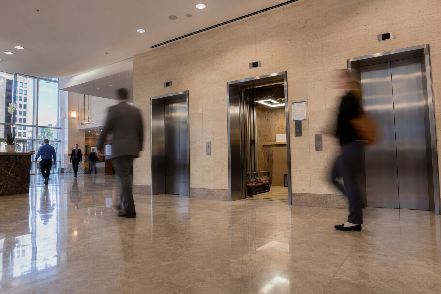 Baltimore office building elevator bank with one cab mid-modernization and two operational cabs, showing phased elevator modernization project avoiding building shutdown