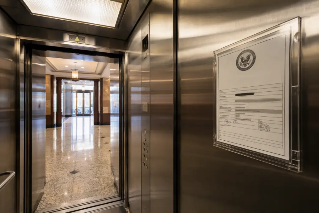 Elevator certificate of inspection posted inside a Washington DC commercial building elevator cab, showing the required conspicuous placement for compliance.
